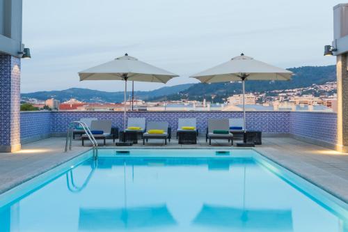 a swimming pool with chairs and umbrellas on a building at Hotel Mercure Braga Centro in Braga