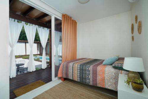 a bedroom with a bed and a balcony with a pool at Corten Villa - A Vacation within Your Vacation in Saint Georgeʼs
