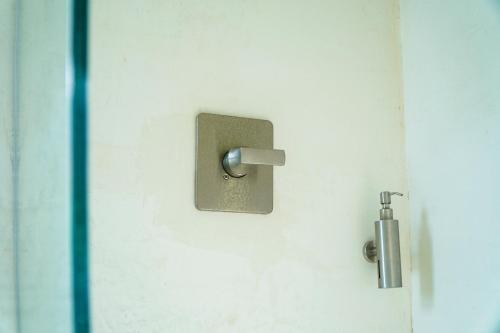 a door with a metal latch on a white wall at Corten Villa - A Vacation within Your Vacation in Saint Georgeʼs