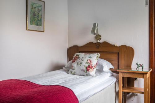 a bed with a red blanket and a pillow on it at Green Hotel in Tällberg