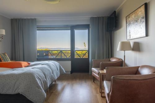 a bedroom with a bed and chairs and a large window at Green Hotel in Tällberg