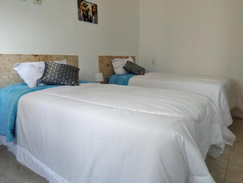 two beds with white sheets in a room at Azure Breeze Hotel in Bayahibe