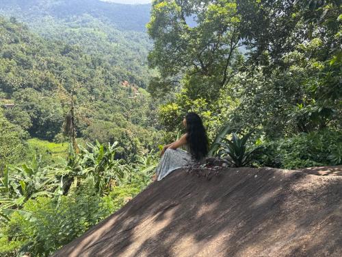 a woman sitting on top of a hill looking at a valley at The Cave in Yatiyantota