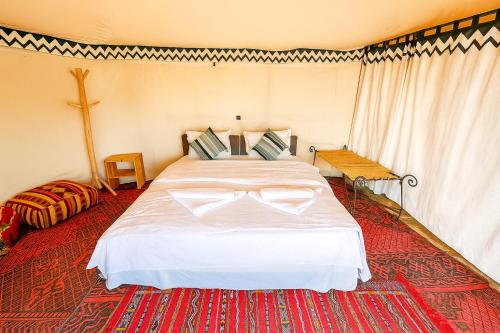 a bedroom with a large bed with a cross on the wall at Ame camp in Merzouga