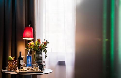 a table with a lamp and a vase of flowers on it at NYX Hotel Bilbao by Leonardo Hotels in Bilbao