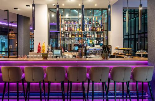 a bar with five bar stools in front of it at NYX Hotel Bilbao by Leonardo Hotels in Bilbao