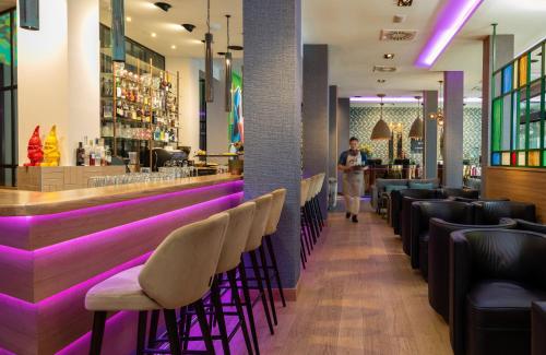 a man walking through a bar with purple lighting at NYX Hotel Bilbao by Leonardo Hotels in Bilbao