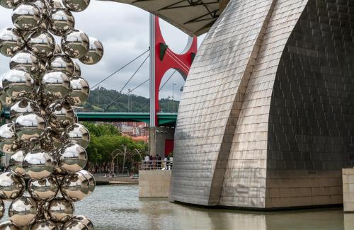 a tall building next to a river next to a bridge at NYX Hotel Bilbao by Leonardo Hotels in Bilbao