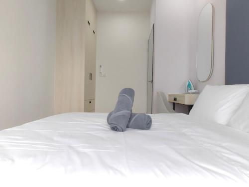 a stuffed animal is laying on a white bed at Vetro11 Beside QEH1 by JUNE Homestay in Kota Kinabalu