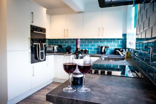 two glasses of wine sitting on a counter in a kitchen at Halford House 3 Bed Town Centre Home from Home with Parking for 2 cars Prime Location Tamworth in Tamworth