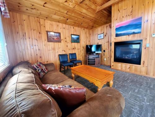 a living room with a couch and a table and a tv at Urban Escape - 1BR King Cabin in Gatlinburg
