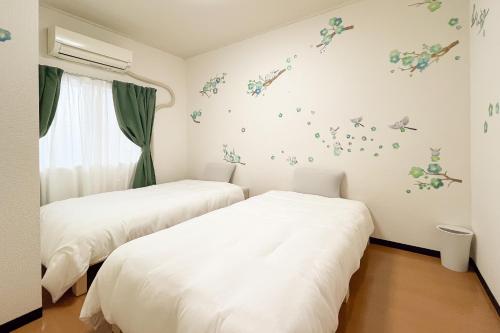 two beds in a room with butterflies on the wall at Wisteria102 無料駐車場有 JR春日井駅徒歩3分の宿 in Kasugai