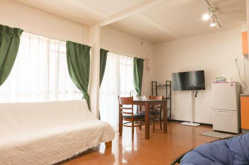 a bedroom with a bed and a table and a tv at Wisteria102 無料駐車場有 JR春日井駅徒歩3分の宿 in Kasugai