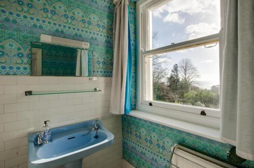 a bathroom with a blue sink and a window at 6 Bed in Branscombe oc-jbetco in Branscombe