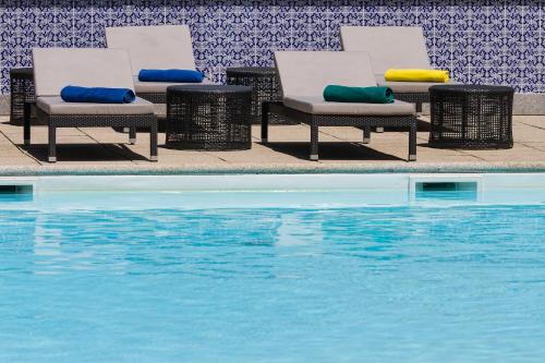 a group of chairs sitting next to a swimming pool at Hotel Mercure Braga Centro in Braga
