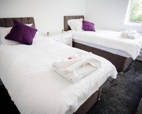 a room with two beds with white sheets and purple pillows at Halford House 3 Bed Town Centre Home from Home with Parking for 2 cars Prime Location Tamworth in Tamworth