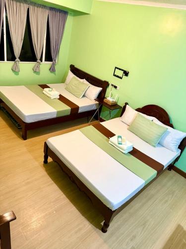 two beds in a room with green walls at Albergo Hotel - Studio Condo Unit - Baguio Transient in Baguio