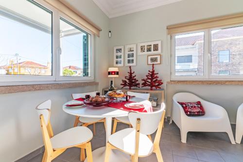 Un comedor con una mesa y sillas blancas. en Casa do Alpendre, en Costa da Caparica