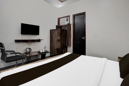 a bedroom with a bed and a desk and a television at Hotel NidhiVan Dham in Mathura