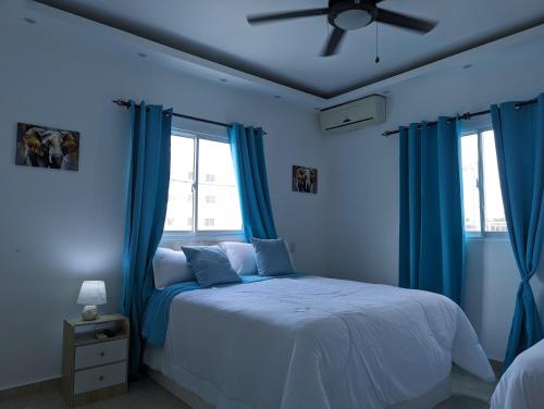 a blue bedroom with a bed with blue curtains at Azure Breeze Hotel in Bayahibe