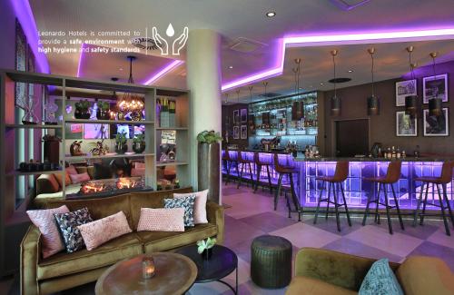 a bar in a restaurant with purple lighting at Leonardo Hotel Dortmund in Dortmund