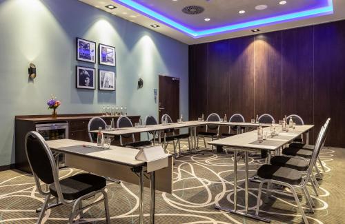 a row of tables and chairs in a room with purple walls at Leonardo Hotel Dortmund in Dortmund