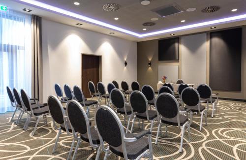 a conference room with chairs and a projection screen at Leonardo Hotel Dortmund in Dortmund