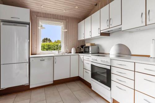 una cucina con mobili bianchi e una finestra di 6681-Allinge-Brunekulvej-2-G ad Allinge