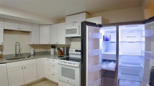 cocina con armarios blancos y nevera abierta en The Vineyard, en Midvale
