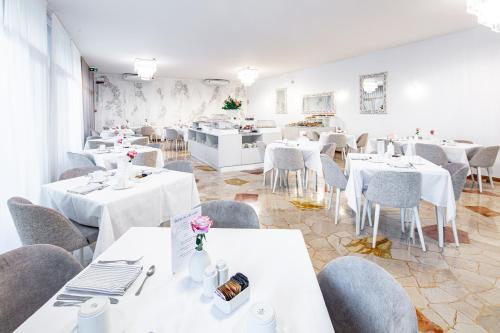 a dining room with white tables and gray chairs at Hotel Centrale in Lignano Sabbiadoro