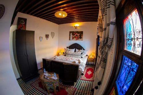 an attic room with a bed and a window at Dar Lalamoune in Fès