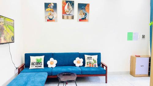 - un canapé bleu dans le salon avec des photos sur le mur dans l'établissement 1988 Homestay Vũng Tàu, à Vung Tau