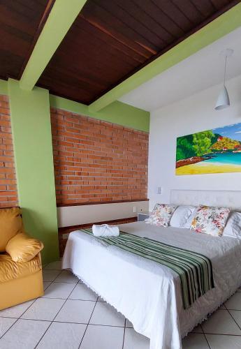 a bedroom with a large bed and a brick wall at Pousada Palmeiras Bombinhas in Bombinhas