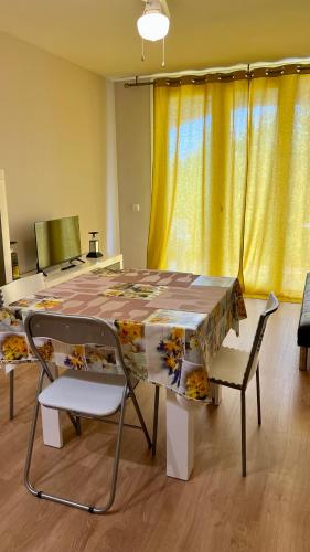エンプリアブラバにあるApartamento cerca del marのテーブルと椅子、黄色のカーテンが備わるお部屋