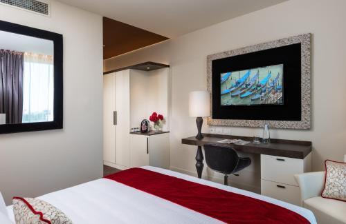 a hotel room with a bed and a desk and a window at Leonardo Royal Hotel Venice Mestre in Mestre