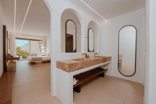 a bathroom with a sink and two mirrors at Muse οf Mykonos Luxury Suites in Mýkonos City