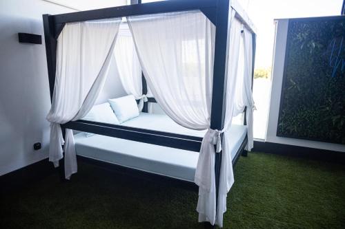 a bedroom with a canopy bed with white curtains at Hotel Macami in El Carpio