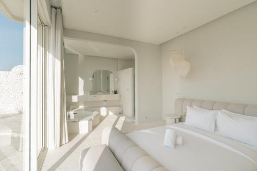 a white bedroom with a bed and a large window at NOUR Uluwatu in Uluwatu
