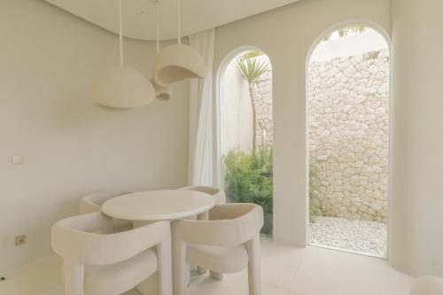 a white dining room with a white table and chairs at Nour Uluwatu in Uluwatu