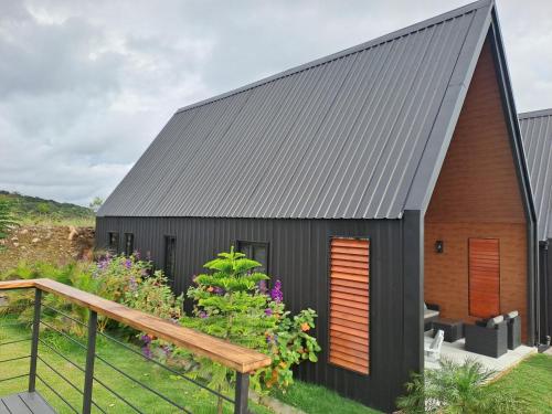 a house with a gray roof and a wooden ramp at Cabañas Piedra del Risco in Alto Boquete