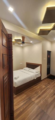 a bedroom with a bed and a wooden floor at Green Suites in Vayalār