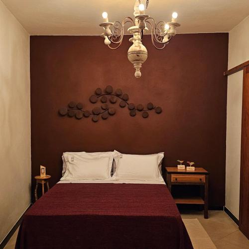 a bedroom with a bed and a chandelier at CASA OURO até seis pessoas com conforto pertim do Centro Histórico in Tiradentes