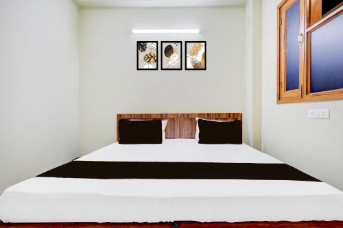 a bedroom with a white bed with black pillows at Hotel O Smile Sweet Hotel in Kalkaji Devi