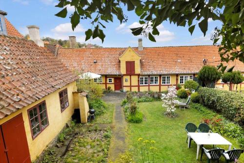 a garden with a table and chairs in front of a building at 5635-Gudhjem-Kirkestien-3 in Gudhjem