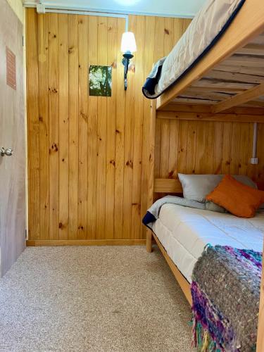 a bedroom with a bunk bed in a wooden wall at Refugio Parque Tepuhueico Zona Costa in Quilán