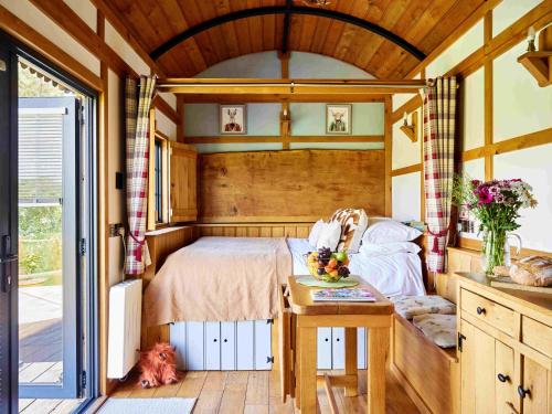 a bedroom in a house with a bed and a table at The Flying Scotsman Shepherd's Hut with Hot Tub in Brecon
