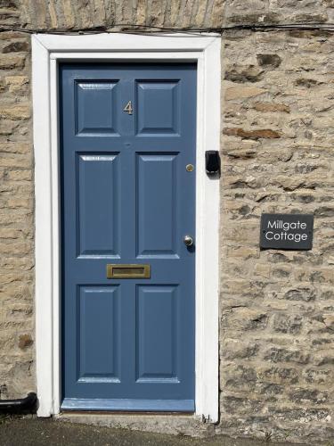 a blue door on the side of a stone building at Millgate Cottage in the heart of Richmond in Richmond