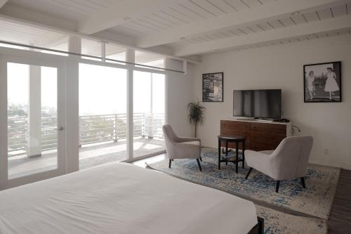 a bedroom with a bed and a television and chairs at Hollywood Hills Hotel in Los Angeles