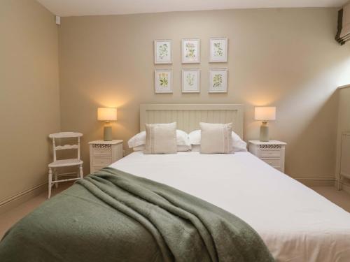 a bedroom with a large white bed with two night stands at Old Cottage Hospital Annexe in Burford