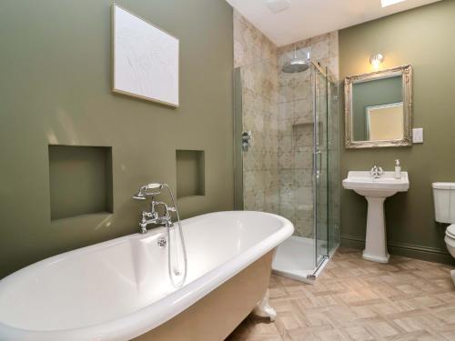 a bathroom with a tub and a toilet and a sink at Old Cottage Hospital Annexe in Burford